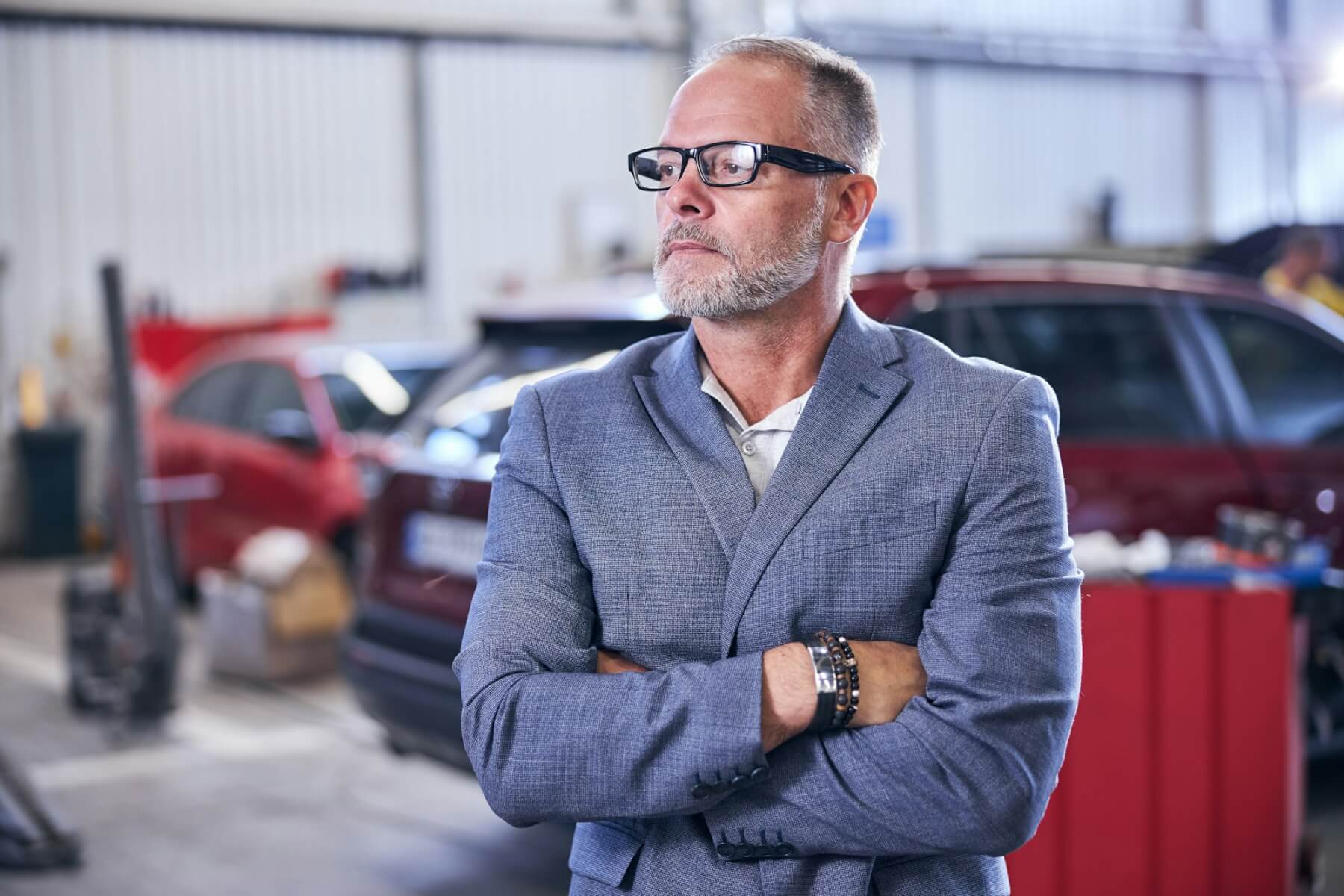 An auto repair shop owner stands confidently | Complete Fire And Security Solutions
